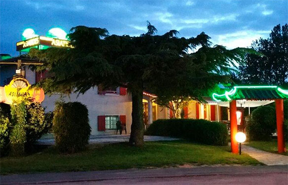 Le restaurant Les Asiatides le soir, avec ses enseignes lumineuses et son entrée pavillon